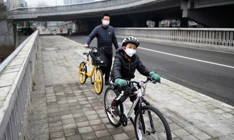 Người dân Bắc Kinh đeo khẩu trang khi đi trên đường phố hôm 20/2. Ảnh: AFP.