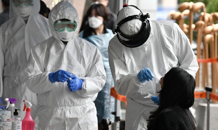Nhân viên y tế Hàn Quốc lấy mẫu xét nghiệm nCoV cho một phụ nữ ở Seoul ngày 10/3. Ảnh: AFP.